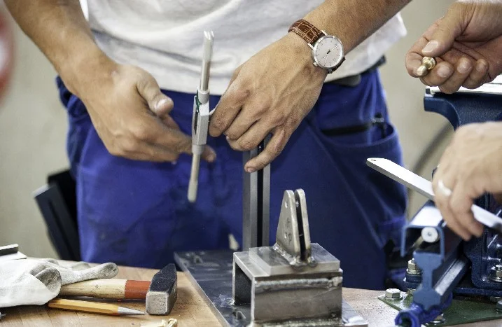 Person misst Metallstück mit Messschieber
